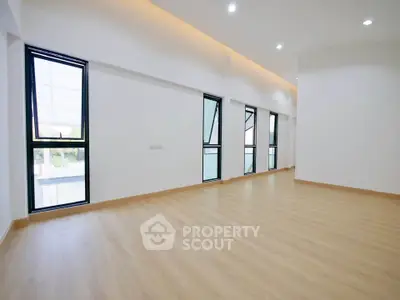 Spacious modern living room with large windows and sleek wooden flooring