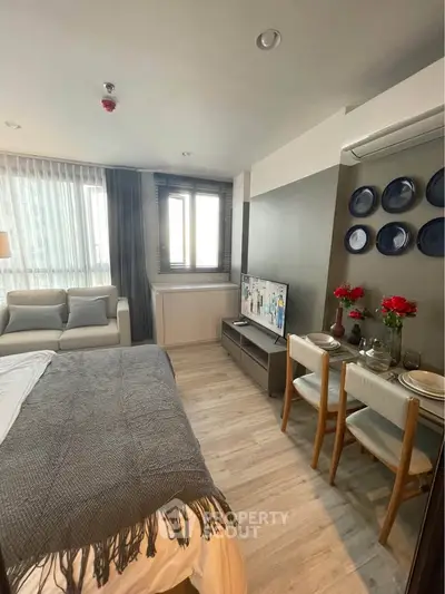 Cozy studio apartment with modern decor, featuring a comfortable bed, stylish dining area, and ample natural light.
