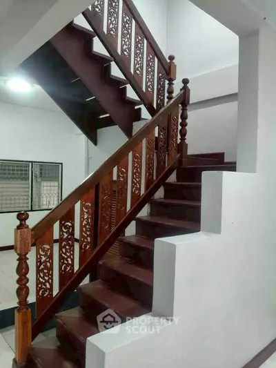 Elegant wooden staircase with intricate railing design in a modern home interior.