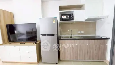 Modern compact kitchen with fridge, microwave, and TV in a stylish apartment.