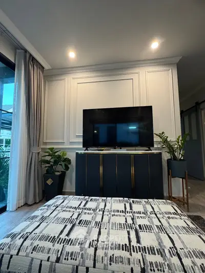 Stylish living room with modern decor and large TV, perfect for relaxation.