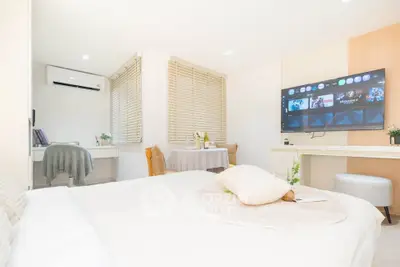 Bright and modern bedroom with stylish decor and wall-mounted TV, perfect for cozy living.