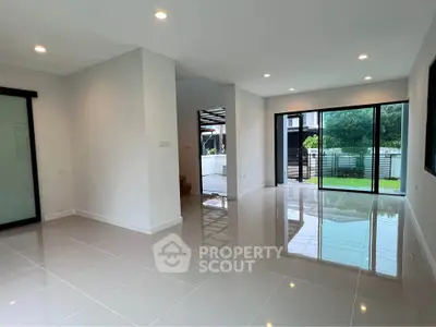 Spacious modern living room with large windows and glossy tiled floors, offering a bright and airy ambiance.