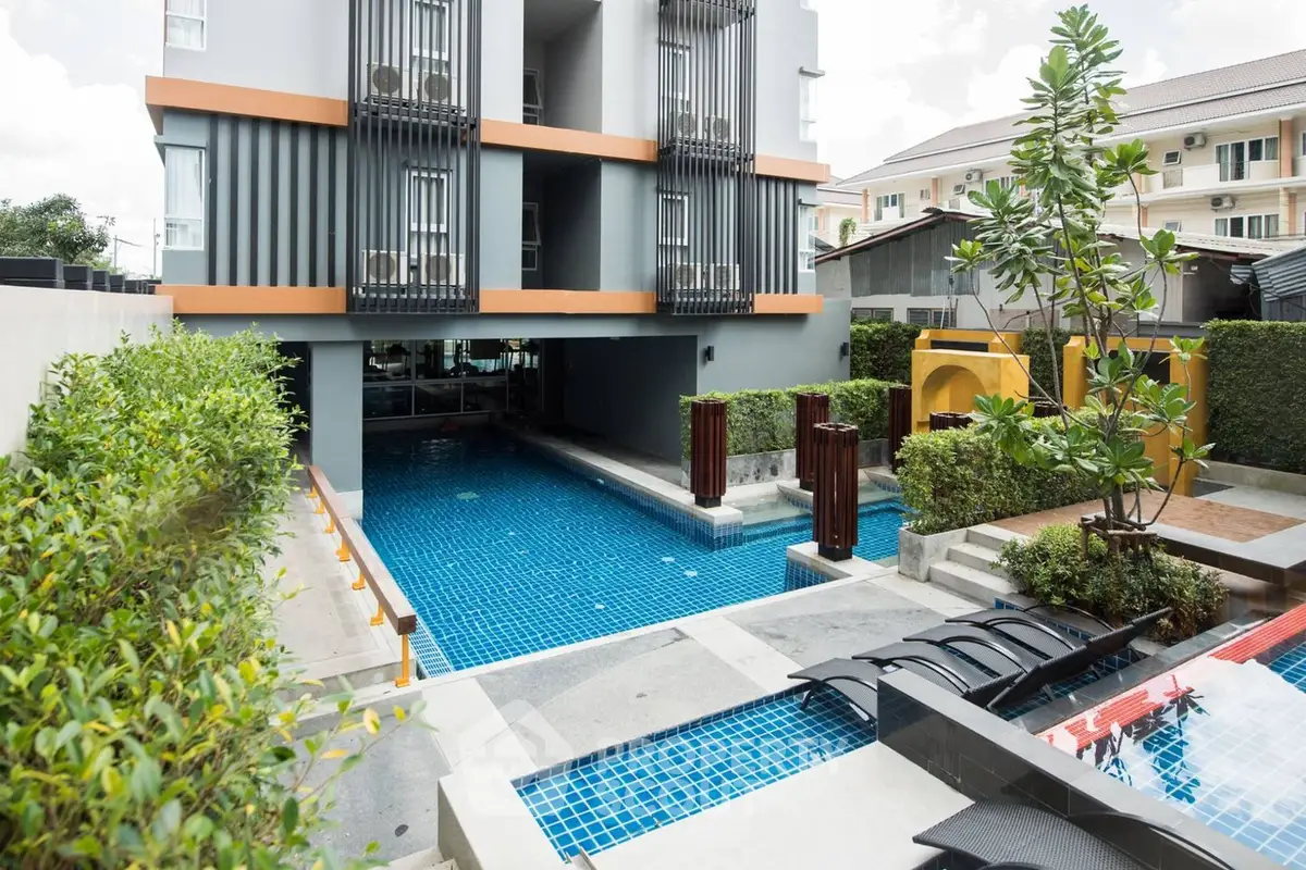Modern residential complex with a stunning communal swimming pool, surrounded by lush greenery and stylish outdoor seating areas.