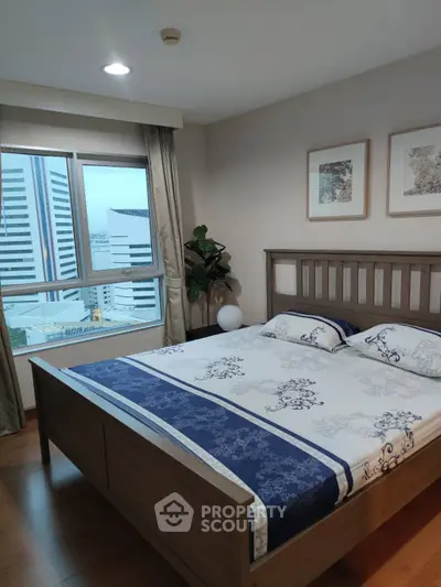 Modern bedroom with city view, featuring elegant wooden bed and stylish decor in high-rise apartment.