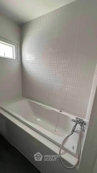 Modern bathroom with sleek bathtub and textured wall tiles, perfect for relaxation.