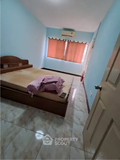 Cozy bedroom with tiled flooring, air conditioning, and natural light from large window.