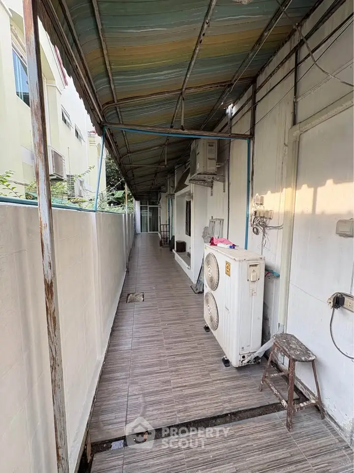 Narrow exterior corridor with tiled flooring and air conditioning units, ideal for utility access.