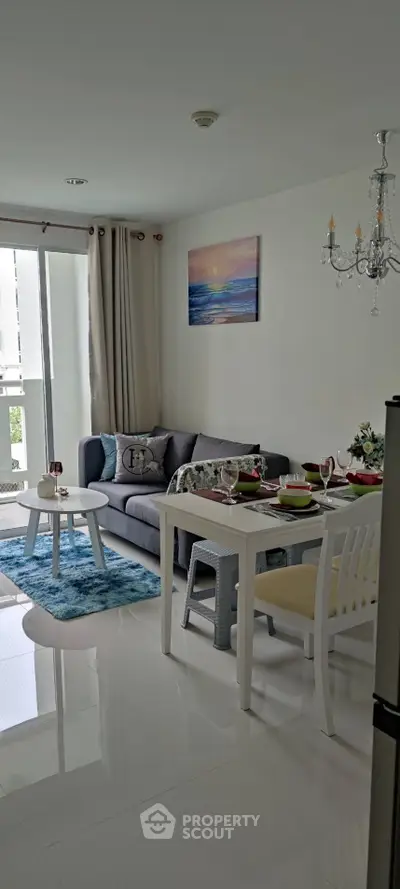 Modern living room with elegant decor and dining area, featuring a cozy sofa and stylish chandelier.