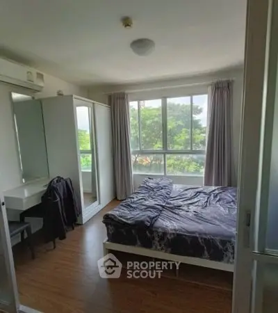 Cozy bedroom with large window and scenic view, featuring modern furniture and natural light.