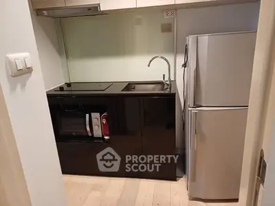 Compact modern kitchen with sleek black cabinetry and stainless steel appliances.