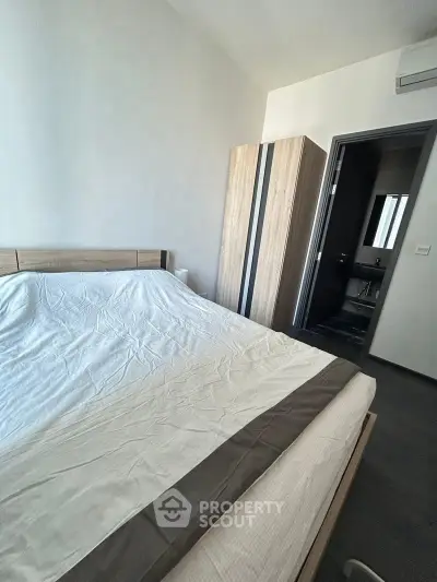 Cozy bedroom with modern wooden wardrobe and ensuite bathroom in a stylish apartment.