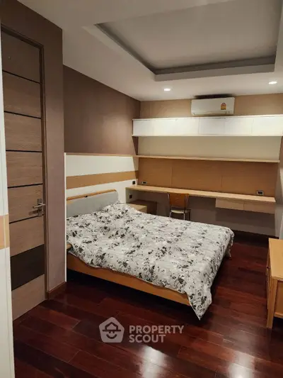 Modern bedroom with wooden flooring and built-in desk, featuring a cozy bed and stylish decor.