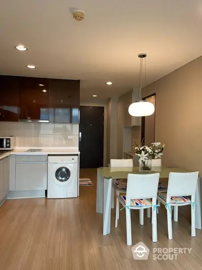 Modern kitchen with dining area and washing machine in stylish apartment