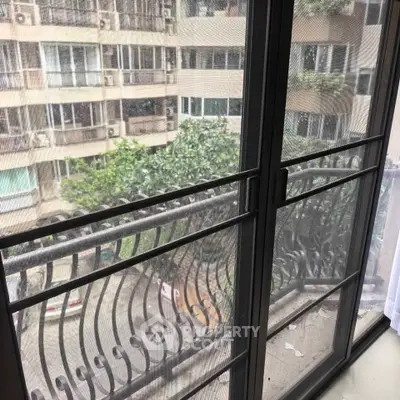 Spacious balcony with elegant railing overlooking lush greenery and urban landscape.