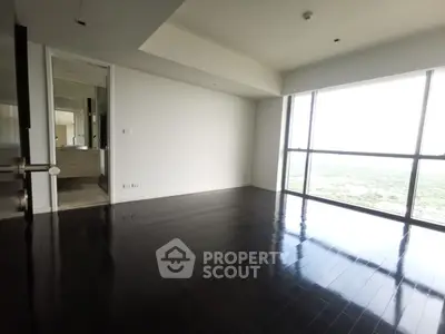 Spacious modern living room with dark wood flooring and large windows offering stunning views.