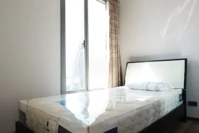 Bright bedroom with large window and modern bed, offering city views.