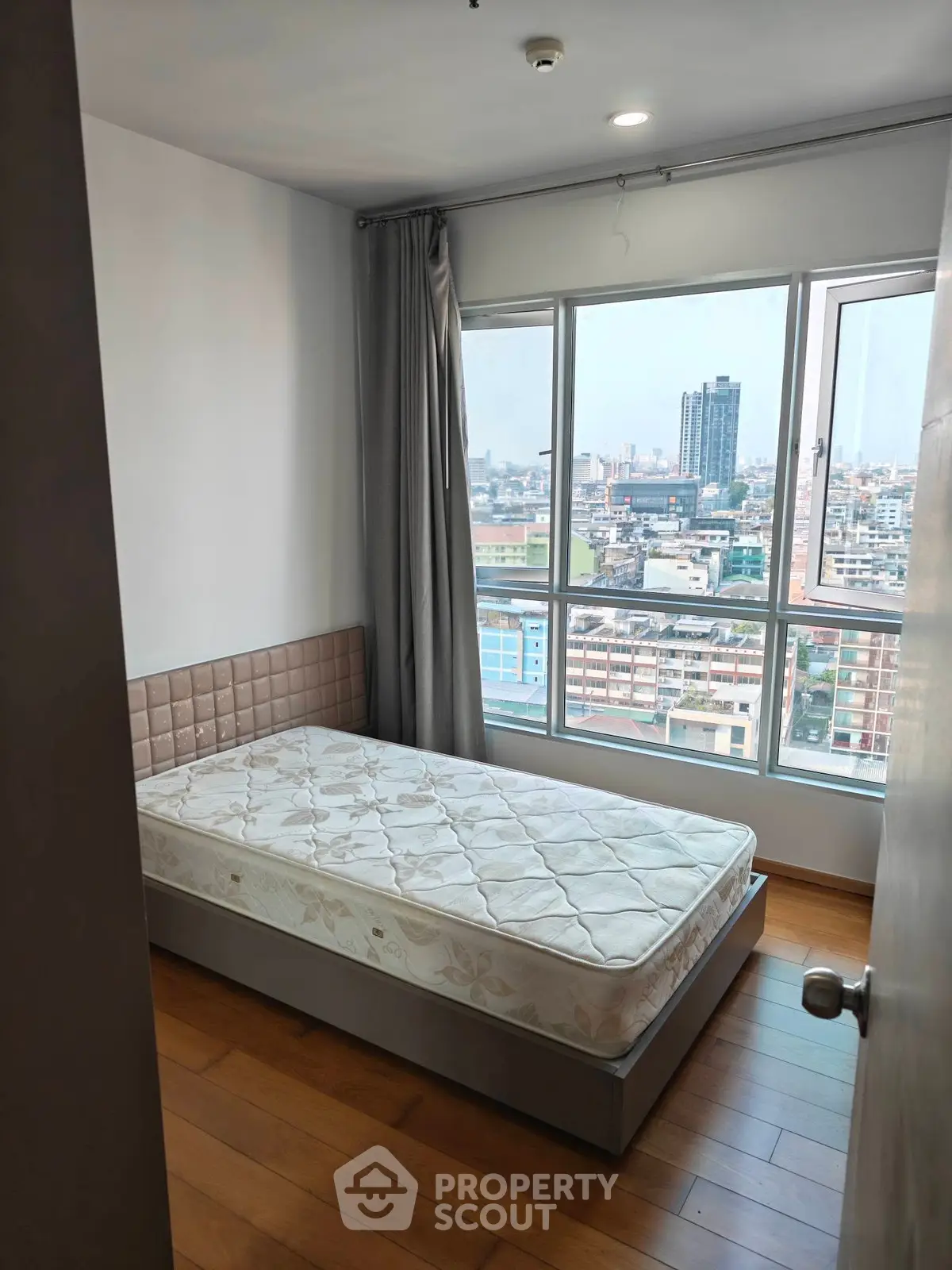 Cozy bedroom with city view, featuring a single bed and large window for natural light.