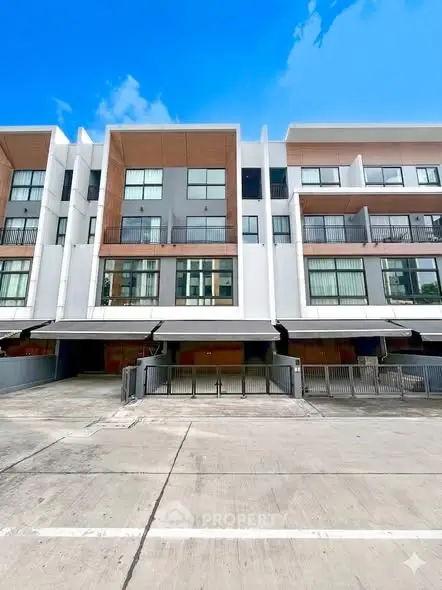 Modern multi-story building with large windows and balconies under a clear blue sky.