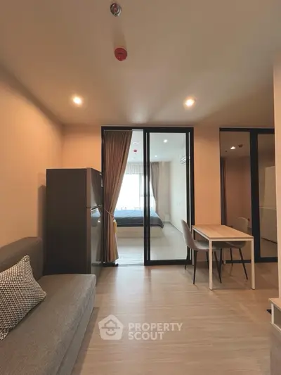 Modern apartment interior with open living and dining area leading to a cozy bedroom.