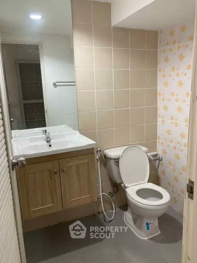 Compact bathroom with sink, toilet, and floral tile accent wall.
