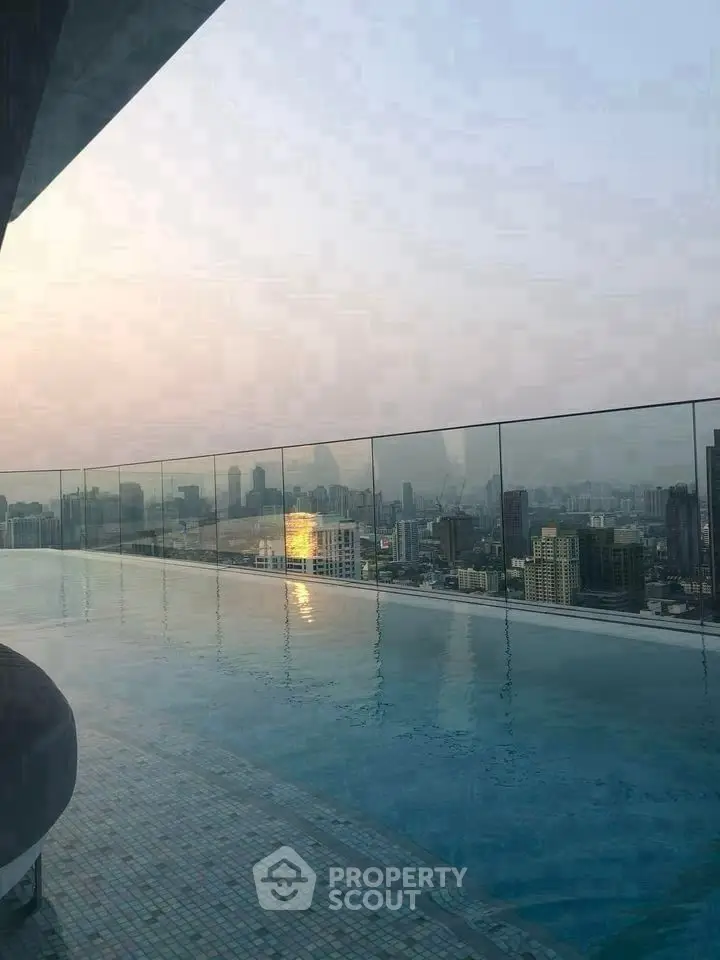 Stunning rooftop pool with panoramic city skyline views at sunset.