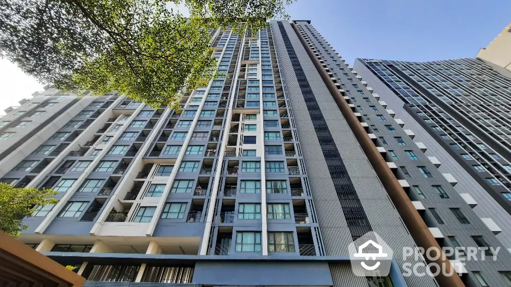 Modern high-rise residential building with sleek architecture and large windows under a clear blue sky.