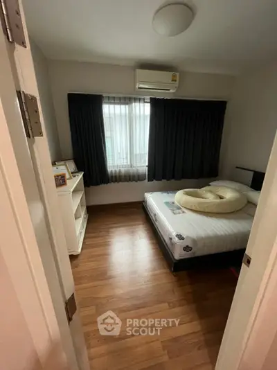 Cozy bedroom with wooden flooring and air conditioning, perfect for restful nights.
