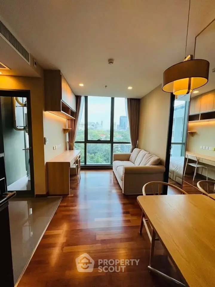 Modern living room with city view, hardwood floors, and cozy furniture in a high-rise apartment.