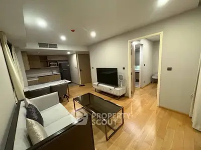 Modern living room with open kitchen, sleek furniture, and wooden flooring in a stylish apartment.