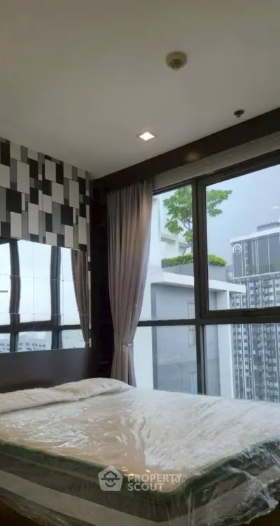 Modern bedroom with large window offering city view in high-rise apartment