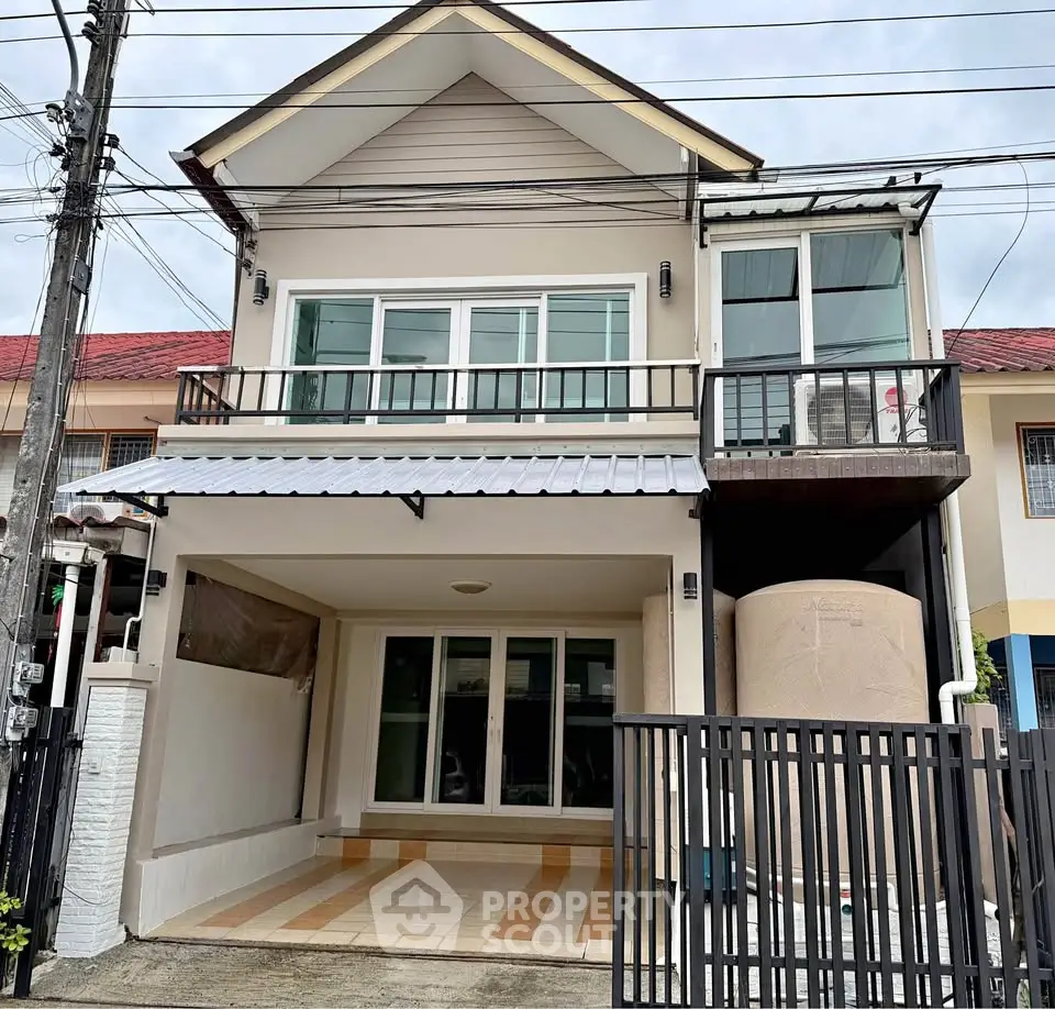 Charming two-story townhouse with modern facade and gated entrance in a suburban neighborhood.