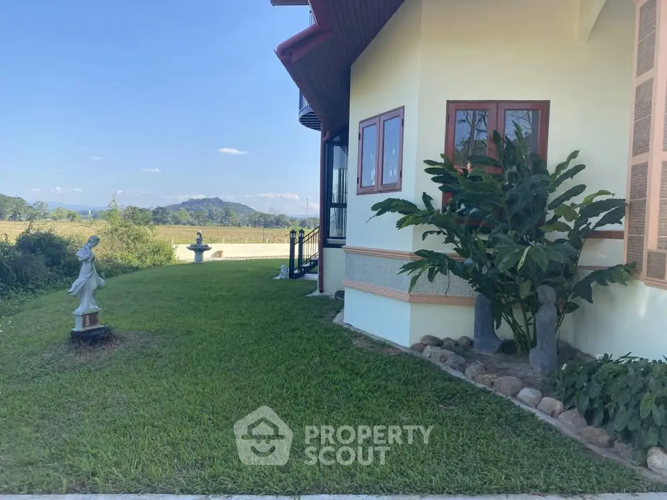 Charming garden view of a countryside home with lush greenery and scenic mountain backdrop.