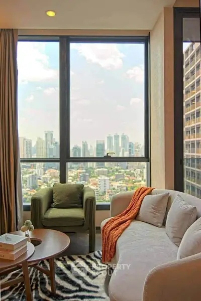 Stylish living room with panoramic city view, cozy seating, and modern decor in high-rise apartment.