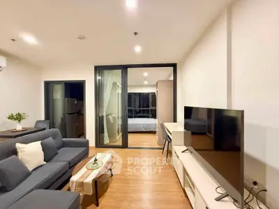 Modern living room with sleek furniture and open view to bedroom, featuring a stylish TV setup and cozy ambiance.