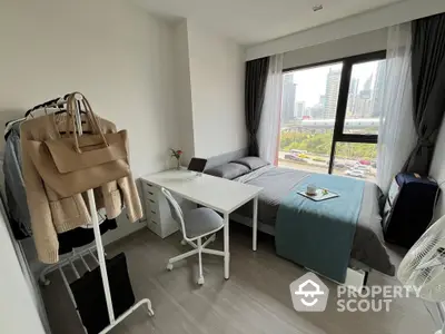 Modern studio apartment with ample natural light, featuring a cozy sleeping area, a dedicated workspace, and a stylish interior design, perfect for urban living.