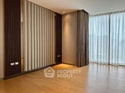 Spacious modern living room with floor-to-ceiling windows and elegant wood flooring.