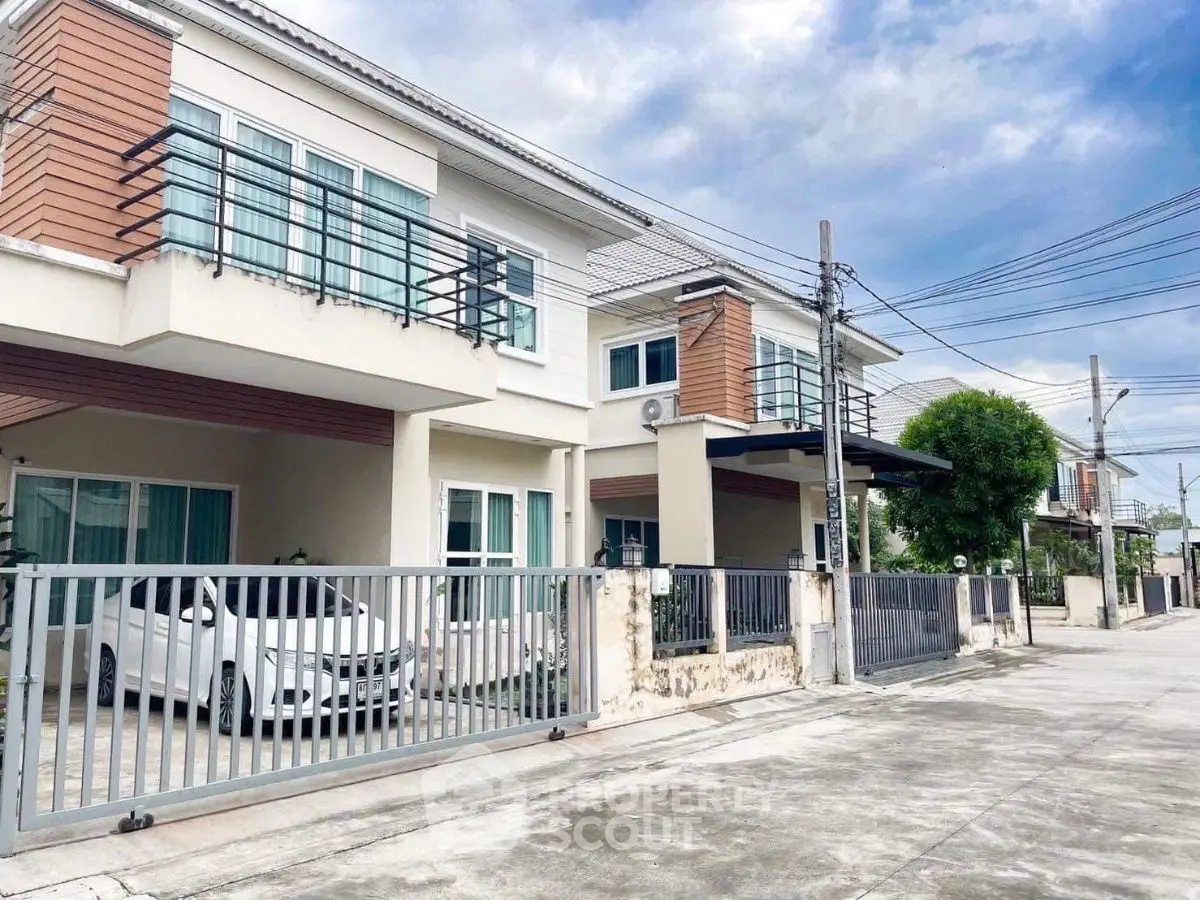 Modern two-story house with gated driveway and car parked outside.