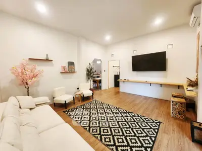 Spacious modern living room with stylish decor and large wall-mounted TV.