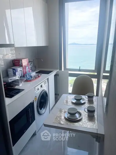 Compact kitchen with ocean view, modern appliances, and cozy dining setup.