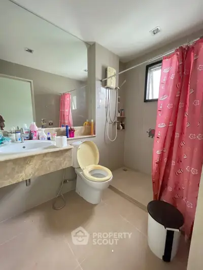Modern bathroom with shower, sink, and toilet, featuring pink shower curtain and ample counter space.