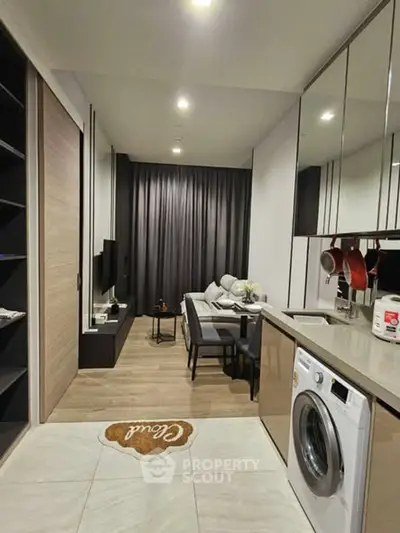 Modern living room with open kitchen and washing machine, sleek design and cozy ambiance.