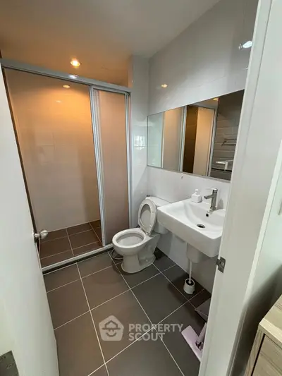 Modern bathroom with sleek design, featuring a glass-enclosed shower and contemporary fixtures.