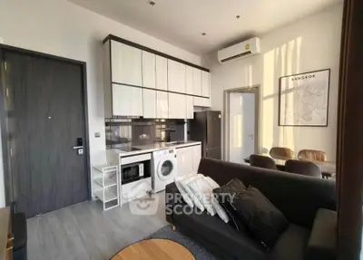 Modern living room with integrated kitchen featuring washing machine and stylish decor in Bangkok apartment.