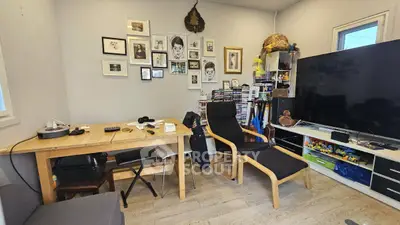 Cozy study room with wooden desk, modern chair, and large TV setup