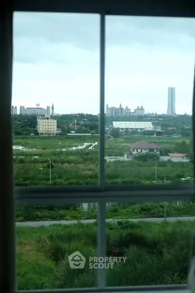 Scenic view from a window overlooking lush greenery and distant buildings.