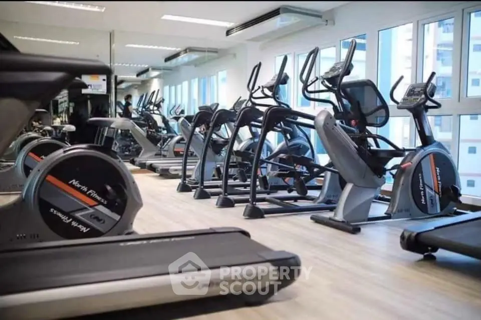 Modern gym with state-of-the-art fitness equipment and large windows for natural light.