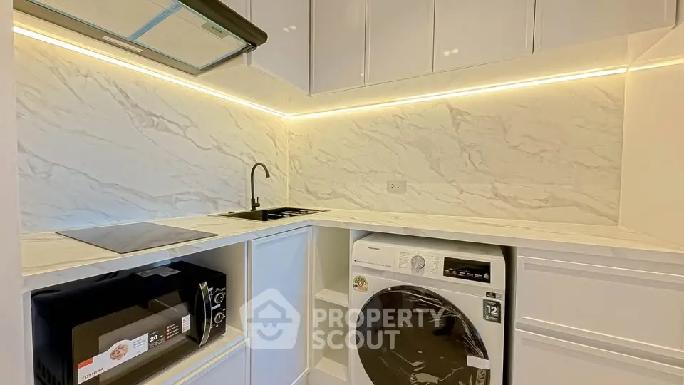 Modern kitchen with marble backsplash, built-in appliances, and sleek cabinetry.