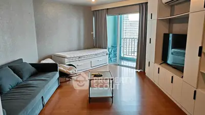 Modern living room with balcony access, featuring sleek furniture and ample natural light.