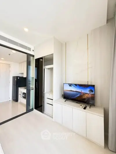 Modern living room with sleek design and integrated kitchen appliances in a bright apartment.